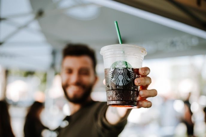 Ein Mann hält einen Starbucks-Behälter hoch, das Logo ist sichtbar